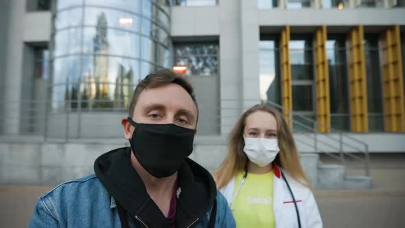 Man Walks with Young Female Doctor with Word "Serious?" on Sweater Both Wearing Face Masks