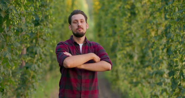 A Portrait of a Farmer Folding His Arms While Standing in the Hop Field