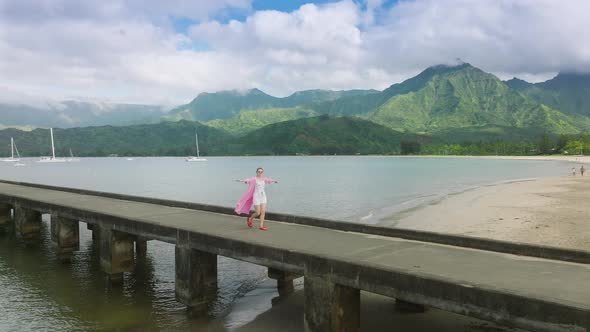 Slow Motion Woman Walking By Pier with Green Mountain Peaks on Motion Background