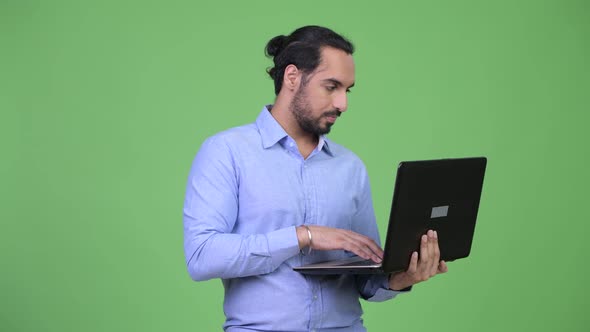 Young Happy Bearded Indian Businessman Thinking While Using Laptop