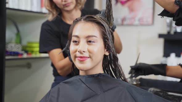 Asian Hairdresser team dyeing coloring beautiful woman customer hair in the beauty salon shop.
