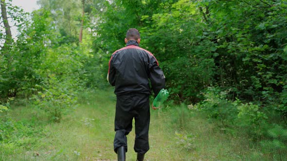 Unrecognizable man throw plastic bottle in nature. Forest pollution