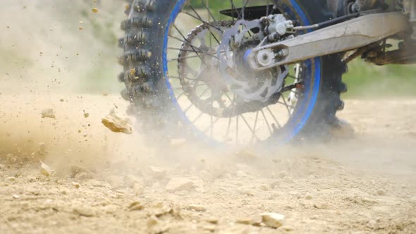 Close Up Wheel of Powerful Off-road Motorcycle Spinning and Kicking Up Dry Ground or Dust