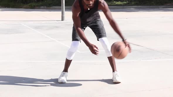 Black man playing basketball on sports ground