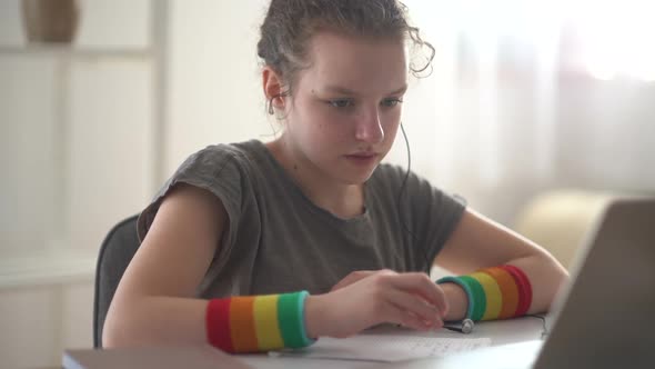 Close Portrait of a Curlyhaired Girl Has Online Lessons Using a Laptop and Headphones