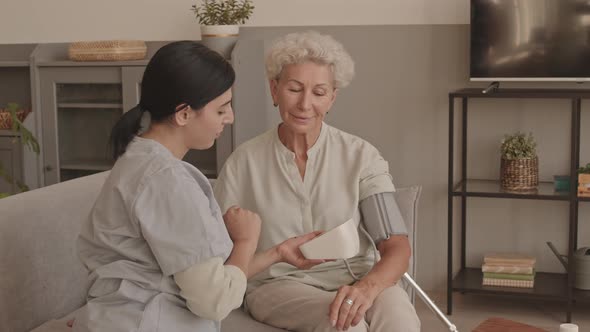 Social Worker Measuring Blood Pressure to Senior Woman