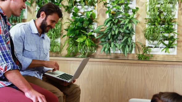 Executives discussing over laptop at desk