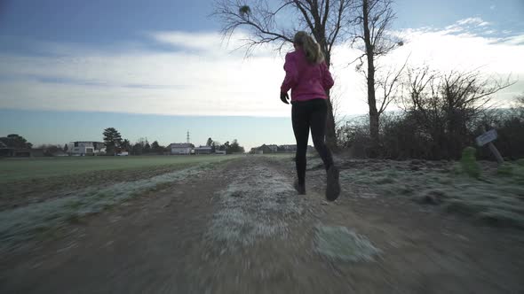 Woman Running on Dirt Track in Autumn Back View