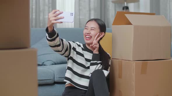 Young Asian Woman With Cardboard Boxes Taking Photo By Smartphone After Moving Into A New House 