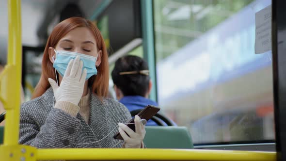 Female Passenger Wearing a Medical Mask and Gloves Listens To Music on Headphones From Her