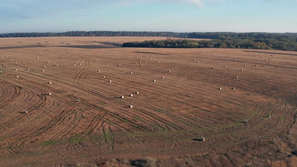 Beautiful morning flight over haystacks. The field is covered with hay.