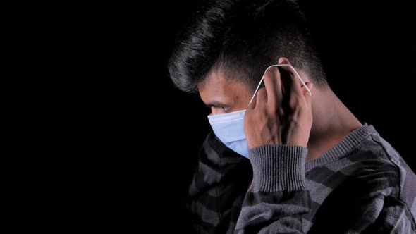 Young Man Wearing Surgical Face Mask Isolated on Black 