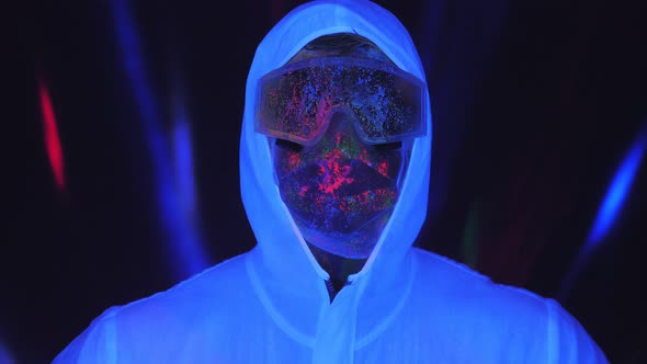 A Male in a White Luminous Suit Mask Splattered with UV Paint in the Dark