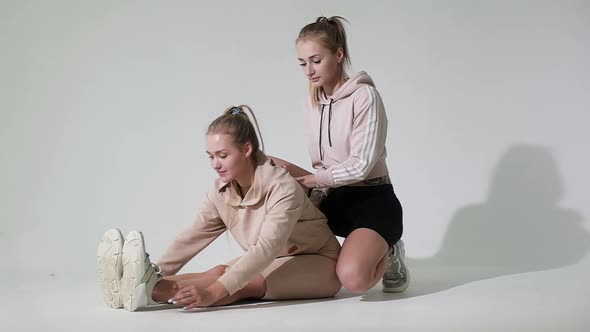 fitness instructor helps girl stretch her body muscles before training