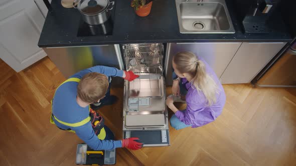 Top View of Woman Looking At Male Technician Checking Dishwasher