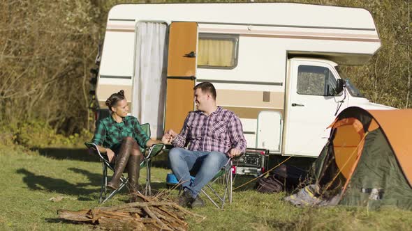 Hipster Couple Sitting on Their Camping Seats and Holding Hands