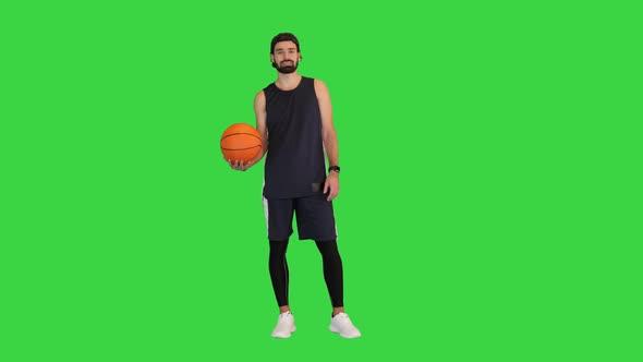 Cheerful Attractive Basketball Player Holding Basketball on a Green Screen Chroma Key