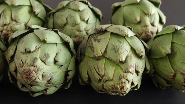 Whole Fresh Artichokes on Black Table