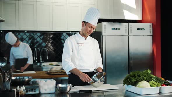 Professional restaurant kitchen: Chef whisking eggs in a bowl