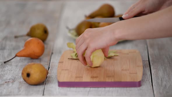 Woman peeling pear for dessert over table.