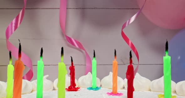 Birthday cake with candles on background of balloons and ribbons.