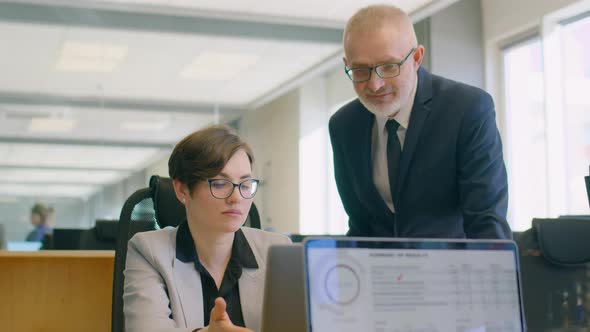 Senior Businessman Helping Female Coworker in Office