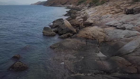 Aerial: A low altitude slow forward flight over the andaman sea and rocky shore with boulders and bi