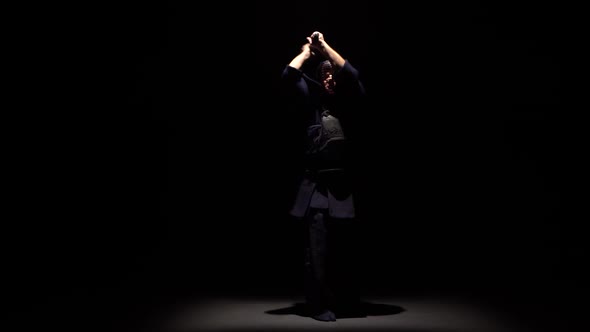 Kendo Fighter Performing Martial Art with Katana Sword at Dark Studio Under Spotlight