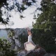 Young Woman in Long White Dress Stands in Yoga Pose on Cliff - VideoHive Item for Sale