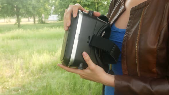 Beautiful Young Woman Looking At A Virtual Reality Helmet In The Park