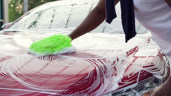 African American which Washing Car Hood with Hand Glove Wiping foam in Outdoors Car Wash Station