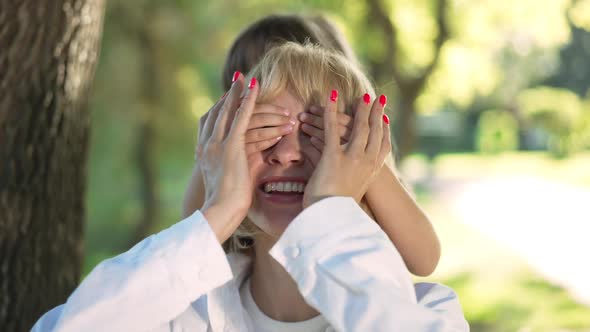 Closeup Portrait of Excited Woman Laughing As Little Girl Covering Eyes with Hands