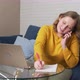 Woman Works at Laptop at Home and is in Hurry Writes Something and Talks on the Phone - VideoHive Item for Sale