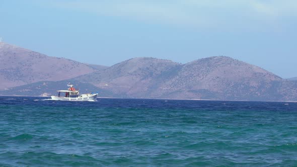 Slow motion of a fishboat set on at aegean sea, with Evia island on there background