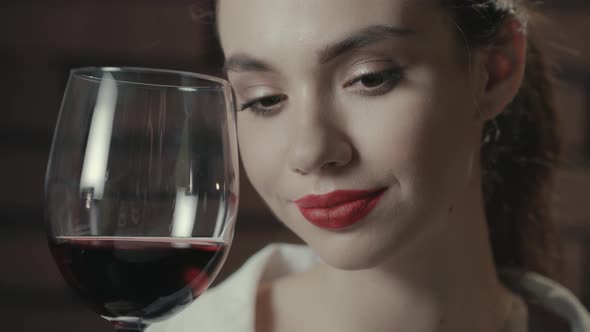 Portrait Beautiful Woman with Red Wine in Wineglass Posing and Looking To Camera