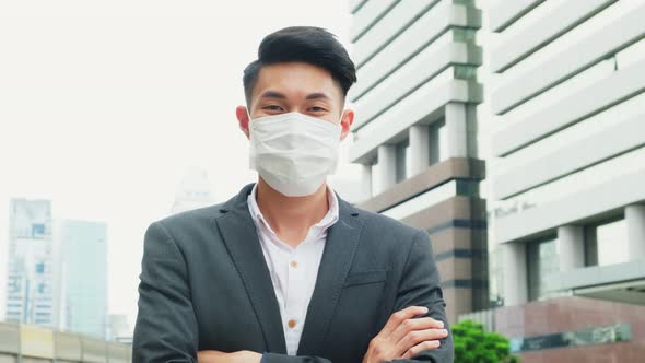 Portrait of Asian office businessman wearing mask standing outdoor in city with new normal lifestyle