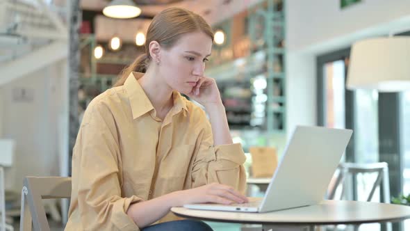 Pensive Young Woman Using Laptop in Cafe