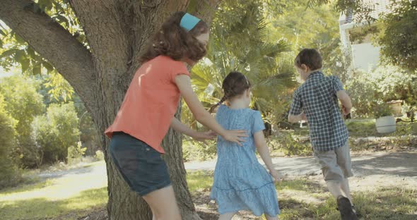 Three kids playing together outdoors on the grass, running around