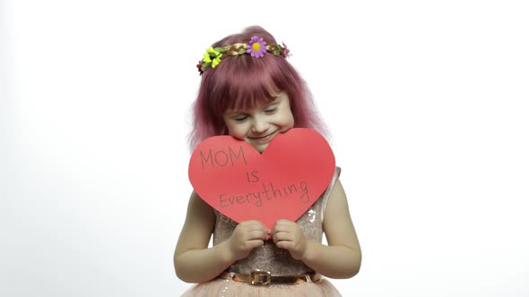 Child Girl Princess Holds Red Paper Heart with Text About Mother. Mother's Day