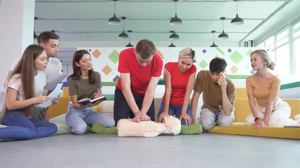 CPR Class with Male Instructor Speaking and Demonstrating Help Giving Lessons of First Aid