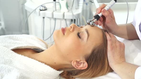 Cosmetologist Uses Iontophoresis for Client's Forehead