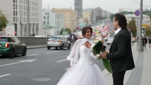 Newlyweds in Megapolis Loving Couple in Wedding Clothes is Walking on Street