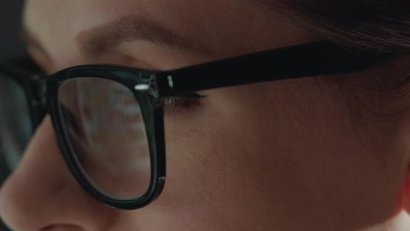 Woman in Glasses Looking on the Monitor and Surfing Internet. The Monitor Screen Is Reflected