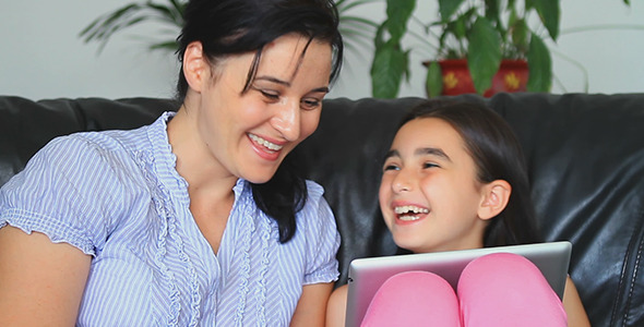 Smiling Mother and Daughter Using Tablet Computer 