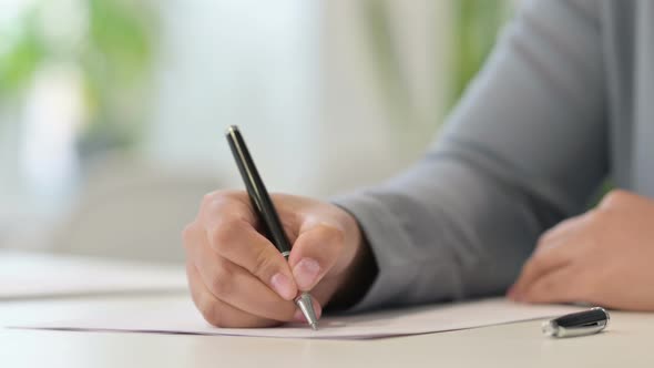 Close Up of African Woman Writing on Paper with Pen