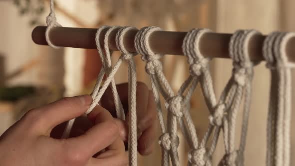 Woman Weaves Pattern Macrame on a Stick in Her Home Workshop