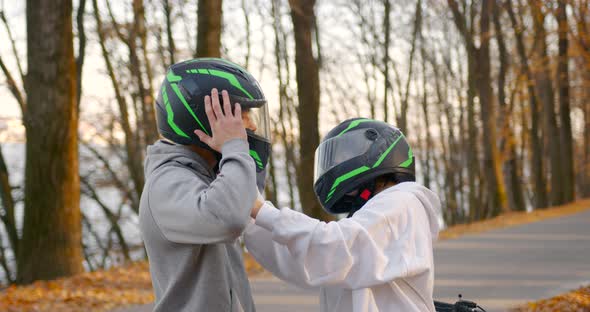 A Young Couple Putting on Helmets in the Autumn Forest