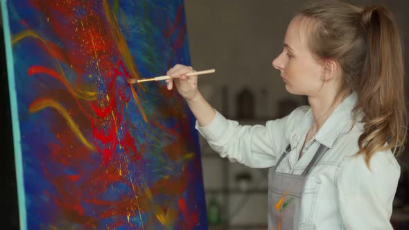 Female Artist in Front of an Easel Painting with a Brush Using Oil or Acrylic Paint