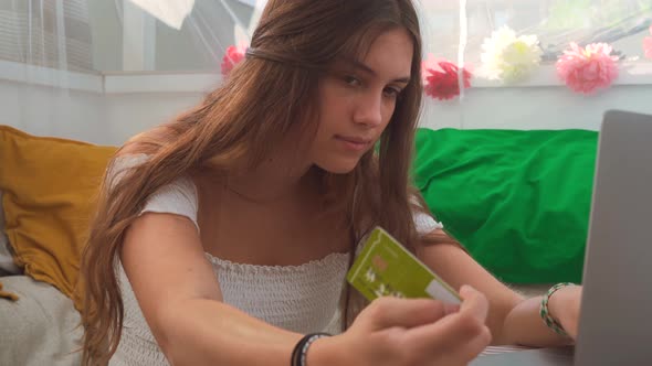 Cheerful woman paying for order with plastic card during online shopping