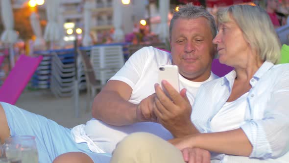 Mature Couple Using Smart Phone on the Beach